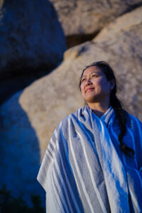 Melissa Roxas looking into the distance. Reflections on trauma, healing and the fatigue we carry.