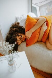 Woman in bed in chronic pain, chronic fatigue, unexplained symptoms. Little Sage blog about emotional wounds can cause chronic fatigue and pain