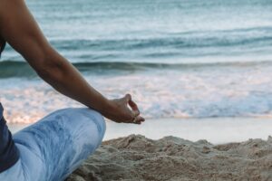 Little sage woman meditate by the beach. Mindful movements in nature.