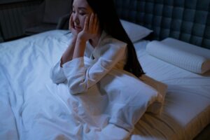 woman in her pajamas sitting up in bed and can't sleep