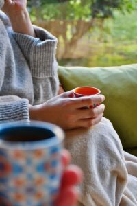 Hands holding a warm cup of tea, part of a summer tea ritual for calming Heart Fire in Chinese medicine