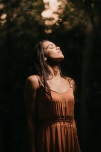 Woman outdoors with eyes closed, looking upward in soft natural light
